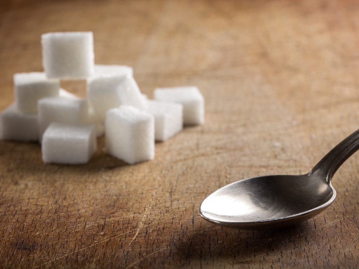 Sugar cubes and a spoon on a wooden surface