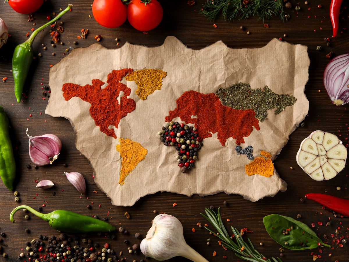 World map made of spices surrounded by fresh vegetables