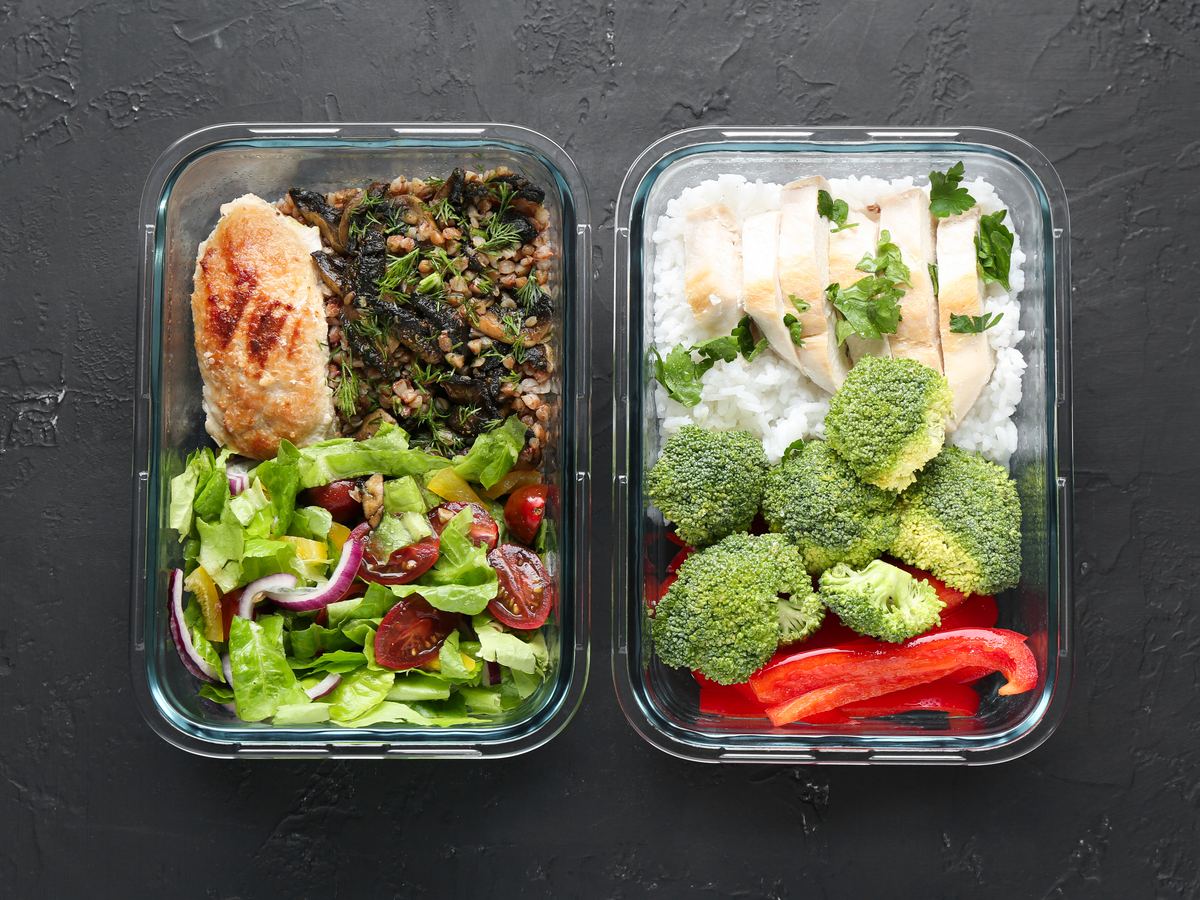 Meal-prep containers with portioned chicken, rice, broccoli and salad