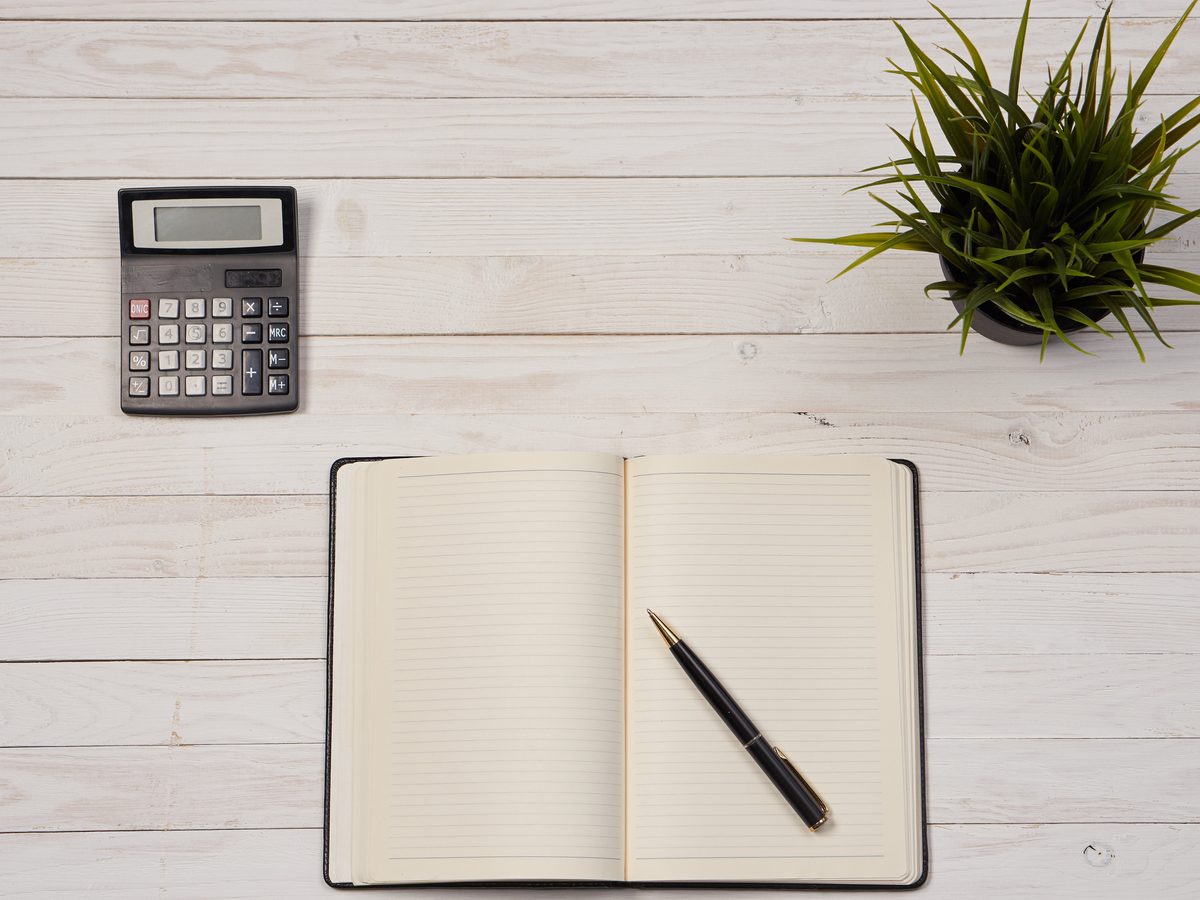 Open notebook, pen and calculator on a white desk