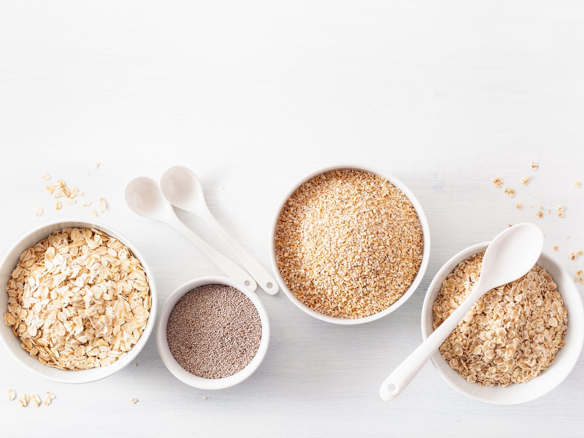 Bowls of oats, bran, psyllium and wheat germ with measuring spoons