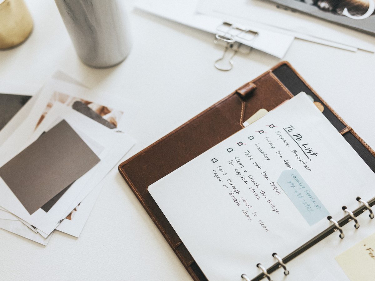 Leather binder open to a handwritten checklist on a white desk
