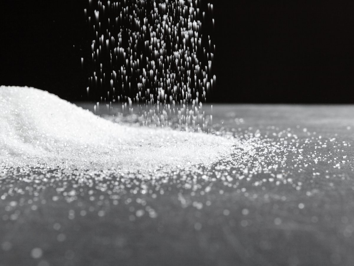 White sugar pouring down onto a mound against a black background