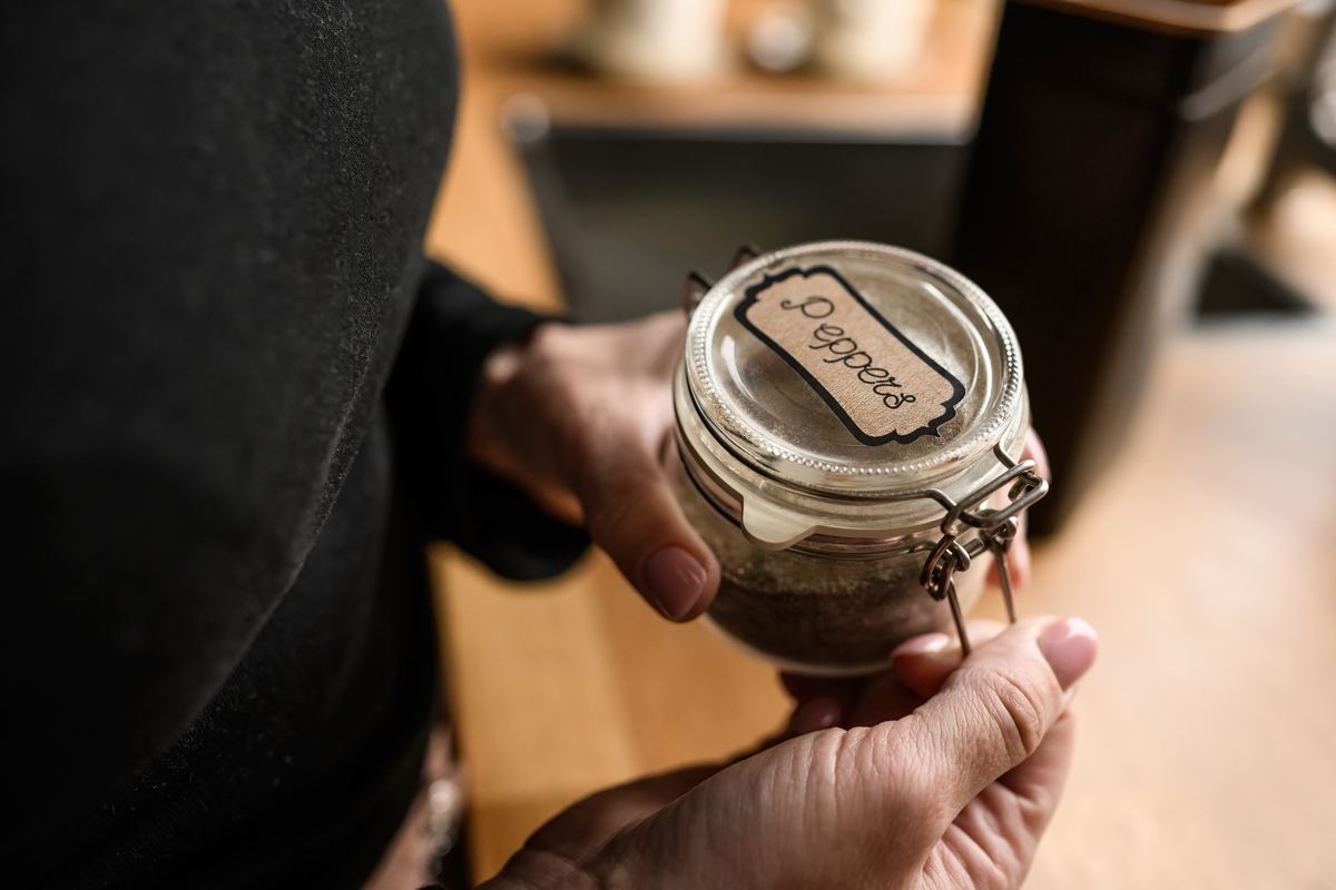 Person holding a labelled jar of ground pepper