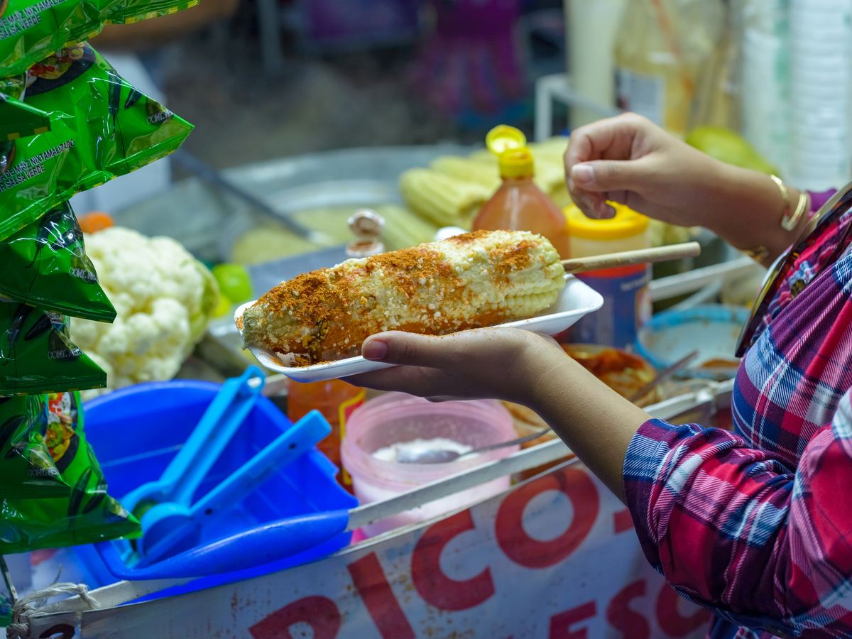 Mexican street food stand with packaged snacks hanging behind the vendor