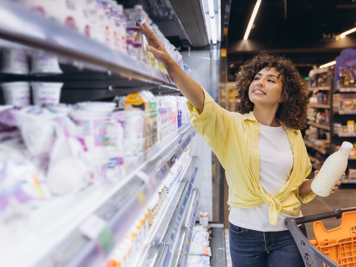 Shopper picking dairy products from a supermarket refrigerated shelf