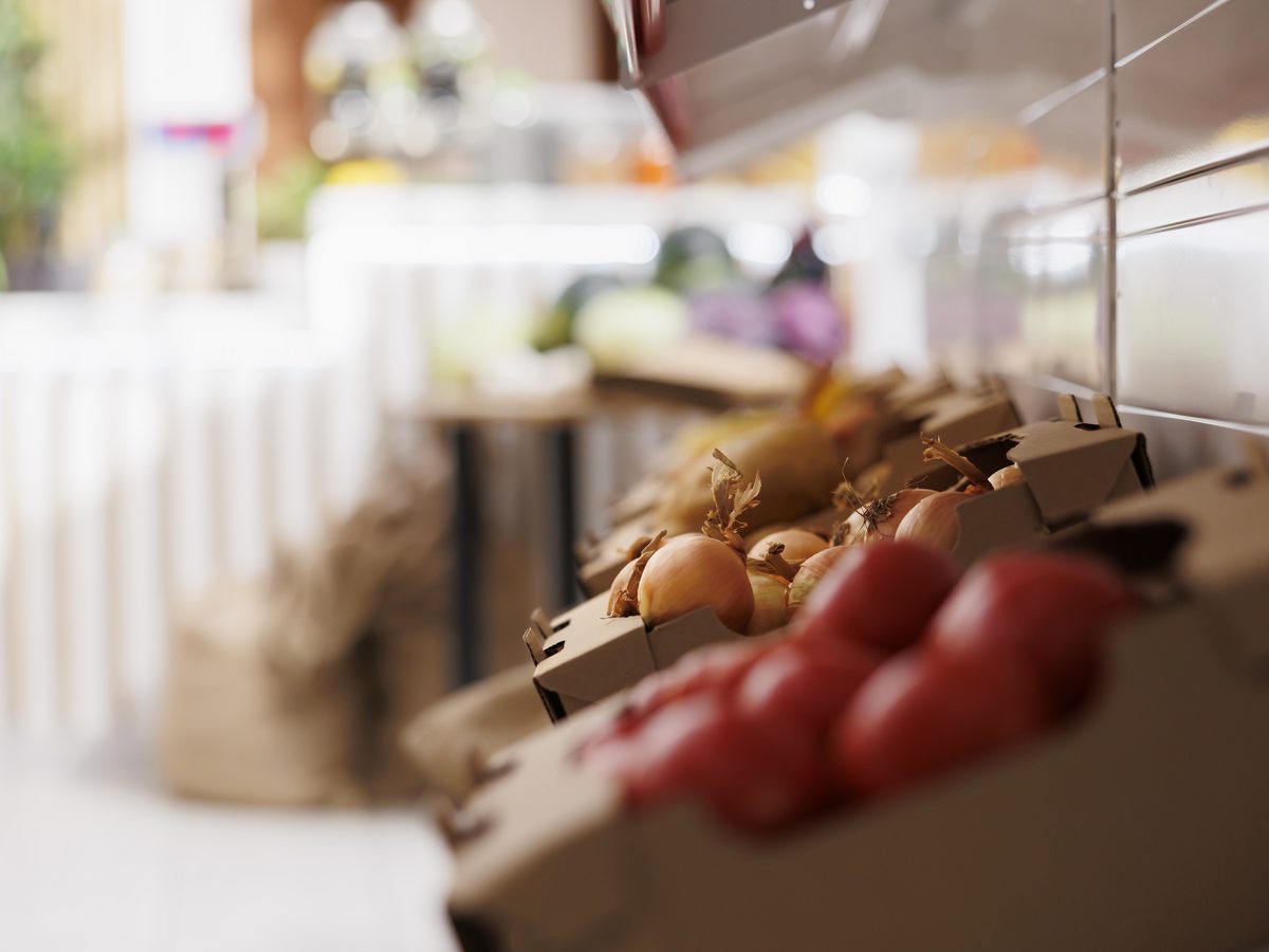 Crates of tomatoes and onions on a grocery shelf, shallow focus