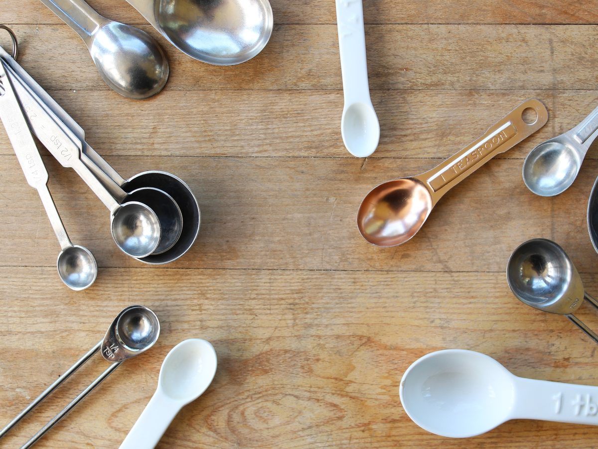 Measuring spoons of different sizes scattered on a wooden board