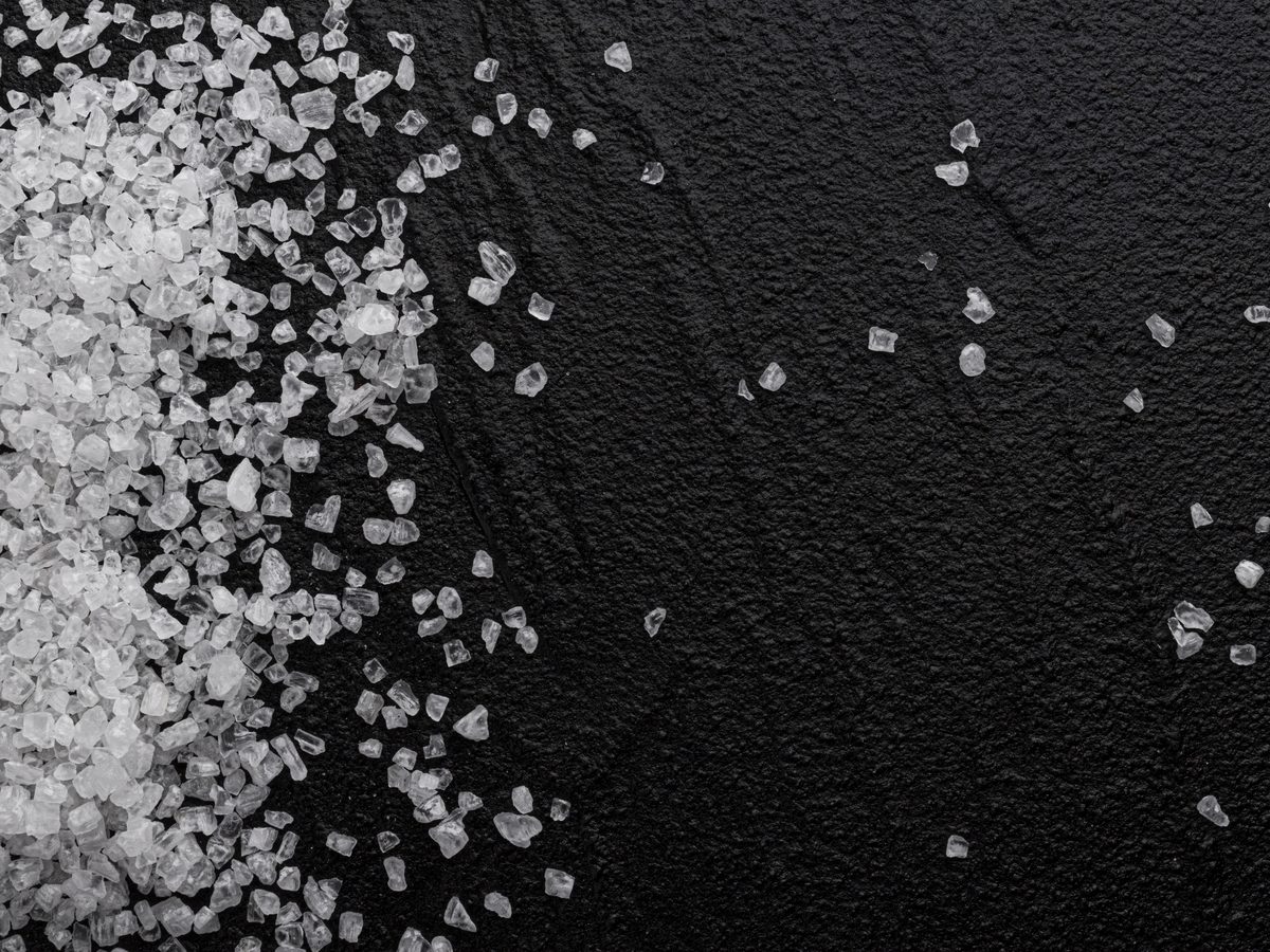 Coarse salt crystals scattered across a black stone surface