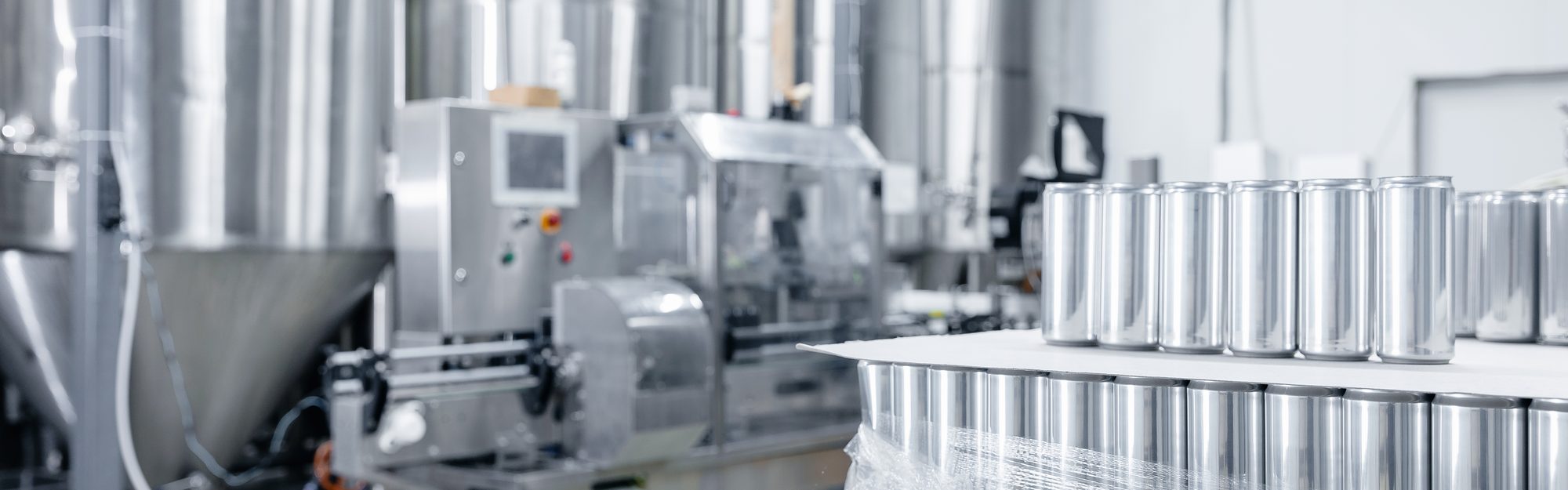 Stainless fermentation tanks and a canning line inside a modern beverage plant